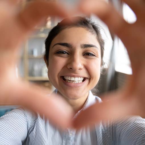 Woman smiling whilst making a heart with her hands